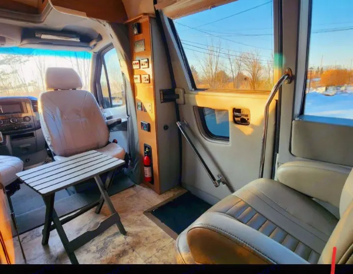 RV rental: Beige camper van interior with driver's seat, folding table, and control panel, bathed in natural light.. Other Other 2016