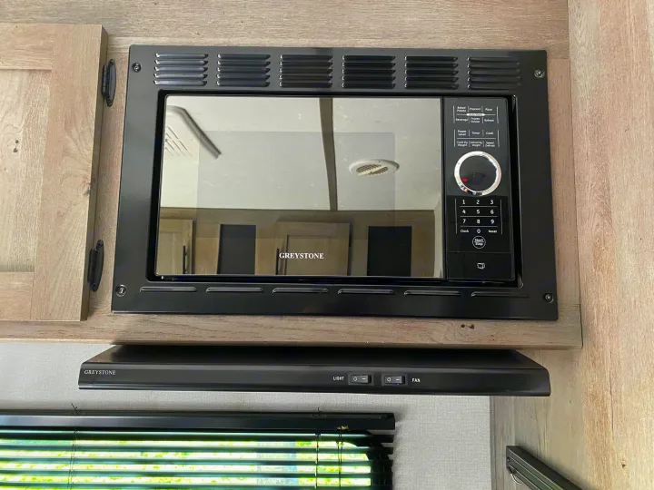 RV rental kitchen: Greystone microwave and range hood installed in a modern RV interior.. Keystone Springdale 2021