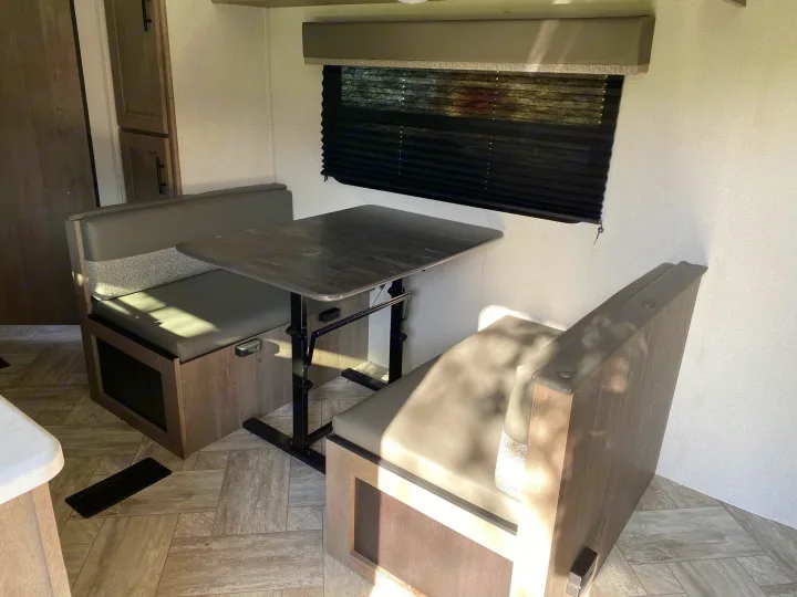 RV rental living space: bright dinette with built-in bench seats, adjustable table, and window blinds, perfect for travel.. Keystone Springdale 2021