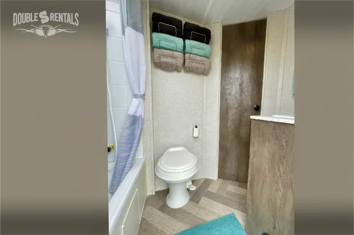 Explore this RV rental's well-equipped bathroom, complete with toilet, shower, vanity, and fresh towels.. Forest River Wildwood X-Lite 2020