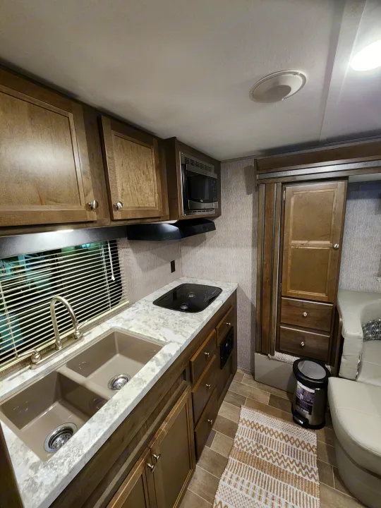 Spacious RV rental interior featuring a full kitchen with microwave, sink, stovetop, and comfortable seating, ideal for travel.. Dutchmen Coleman Light LX 2020
