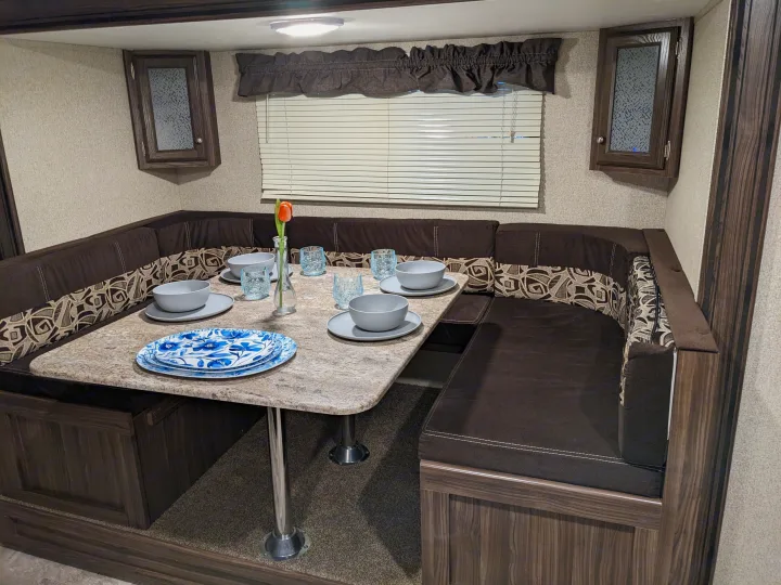 Cozy RV rental dinette with U-shaped seating, a spacious table, and full place settings for comfortable meals.. Coachmen Apex LE 2018