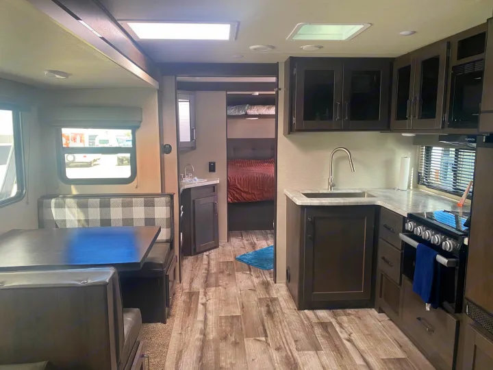 Explore this modern rv rental interior! Features a cozy dining area, full kitchen, and private sleeping quarters.. Grand Design Transcend 2022