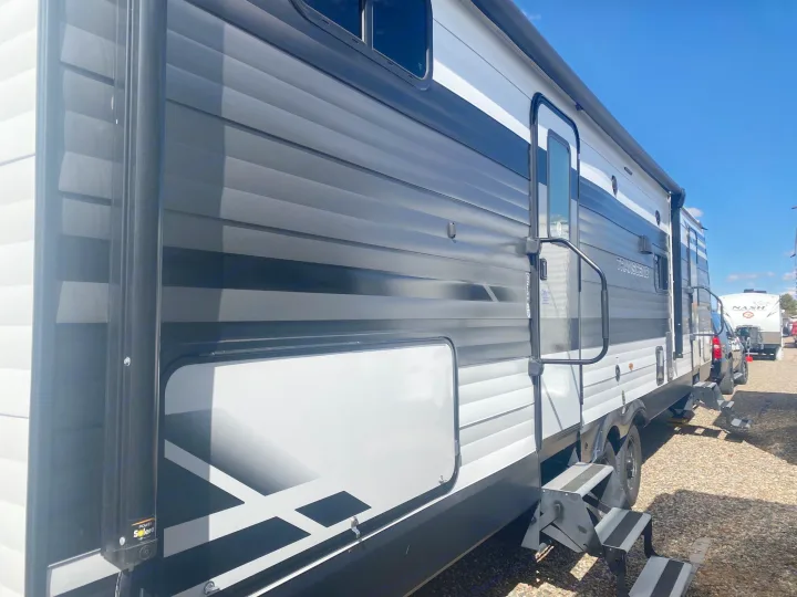 Exterior of a sleek black, white, and grey rv rental travel trailer, featuring entry steps and a storage compartment.. Grand Design Transcend 2022