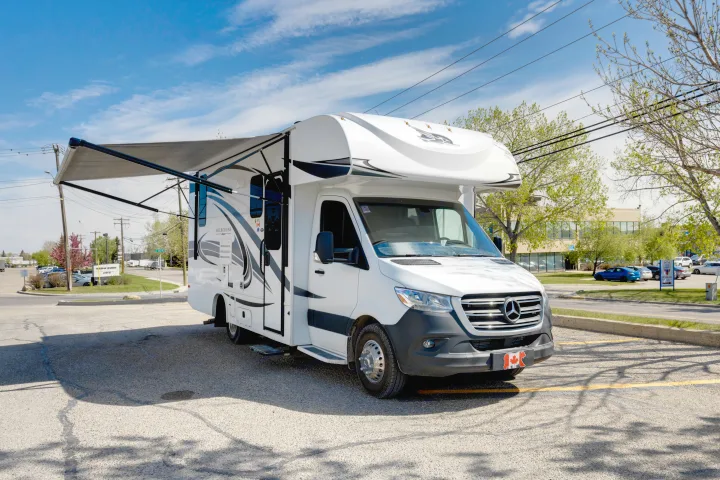 A clean white Mercedes-Benz Jayco Melbourne RV rental is parked with its awning extended in a sunny lot.. Jayco Melbourne 2022
