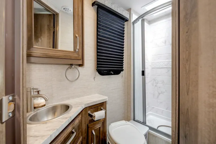 Compact RV rental bathroom with a sink, vanity, toilet, and full shower, designed for comfortable travel.. Jayco Melbourne 2022
