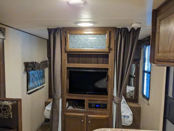 Experience an RV rental's comfort: TV, storage, and a private sleeping area with curtains.. Coachmen Apex LE 2018