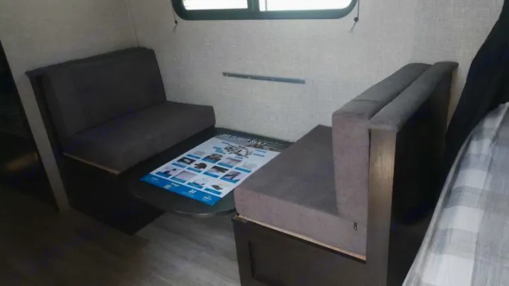 RV rental dinette with cozy gray benches, a small table, and a window. Ideal compact travel space.. Jayco Jay Flight SLX 2022