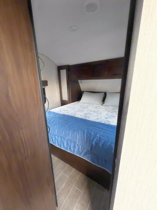RV rental bedroom showcasing a comfortable bed, overhead storage, and modern flooring, viewed from the doorway.. Forest River Grey Wolf 29te 2021