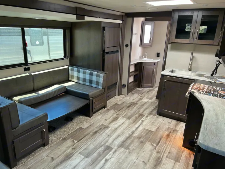Spacious RV rental interior featuring a kitchen with sink, dinette seating, and a bathroom vanity area.. Grand Design Transcend Xplor 2022