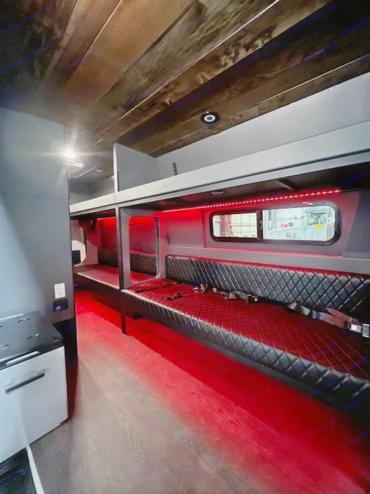 RV rental's custom interior: black diamond-quilted seating, bunk beds, and bright red LED lighting creating a lounge vibe.. Mercedes Sprinter Freight Liner 2020
