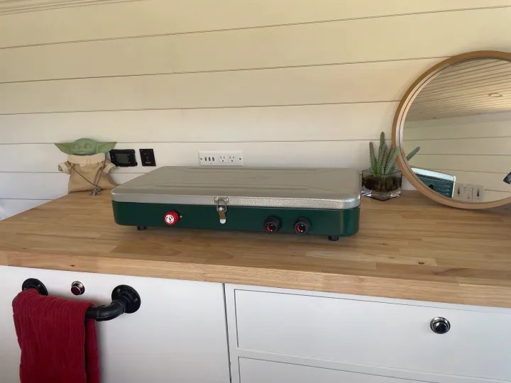 RV rental interior showcasing a portable stove, wooden counter, Grogu, and modern outlets, perfect for mobile adventures.. Dodge Ram 3500 2003