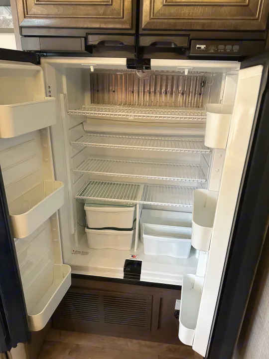 Open, empty RV rental refrigerator interior with wire shelves and door bins, ready for your next adventure.. Jayco Greyhawk 2023