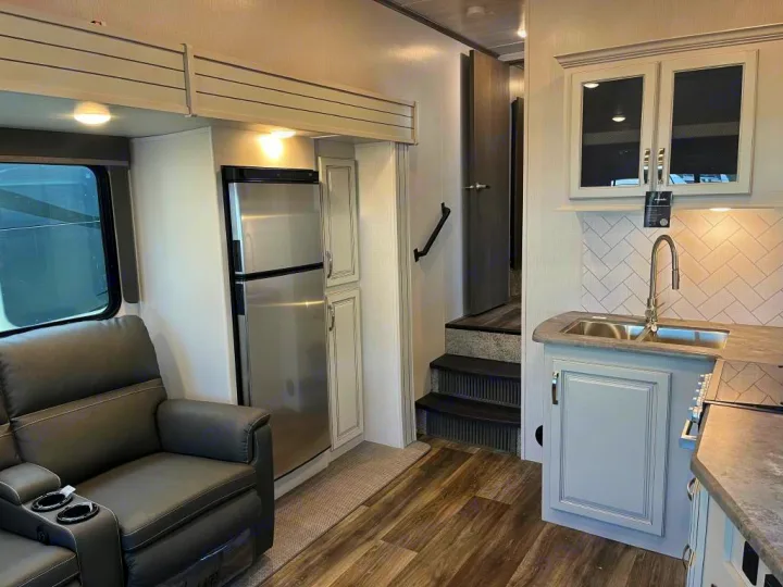 Explore this RV rental's spacious interior, featuring a modern kitchen, comfortable living area, and stairs to another level.. Keystone Cougar 2022