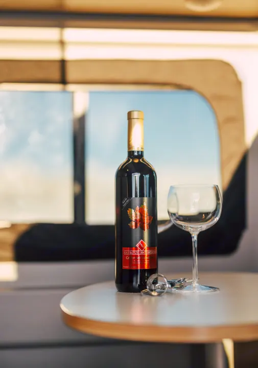An organic Cabernet Sauvignon bottle, glass, and opener on a table inside an RV rental. Perfect for travel.. Winnebago Solis 2022