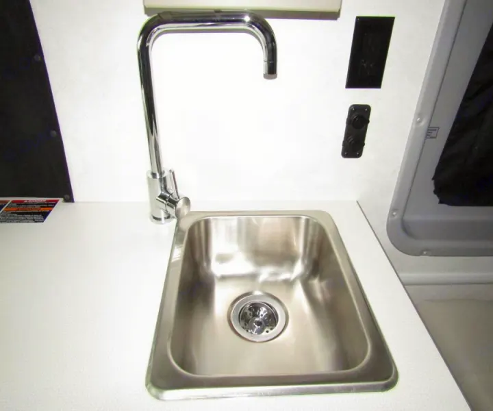 RV rental: Compact kitchen area with a stainless steel sink, chrome faucet, and white countertop in an RV or camper.. Winnebago Solis 2022