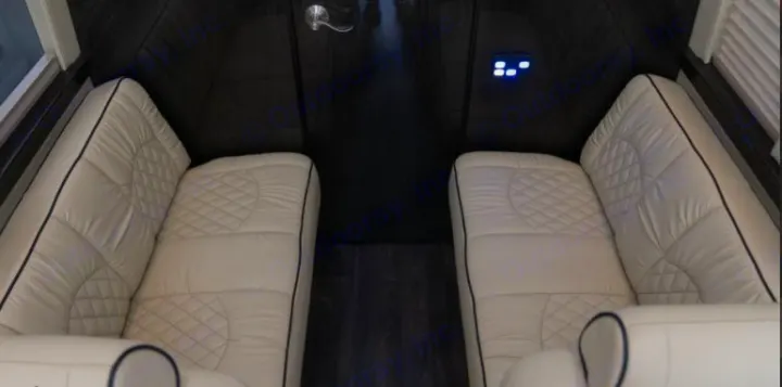 Inside an RV rental: Cream-colored, quilted seating and dark wood floors define this luxury interior with controls.. Midwest Automotive Designs Daycruiser 2019