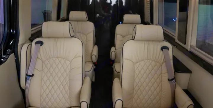 Luxury RV rental interior showing two rows of cream leather captain's chairs with diamond stitching and seatbelts.. Midwest Automotive Designs Daycruiser 2019