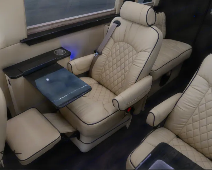 Inside a luxury RV rental: cream leather captain's chairs with a fold-out table and elegant wood trim for comfortable travel.. Midwest Automotive Designs Daycruiser 2019