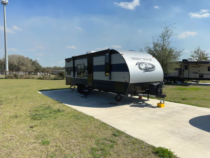 This Grey Wolf travel trailer is set up at a sunny campsite, perfect for an RV rental adventure.. Forest River Cherokee Grey Wolf Special Edition 2022