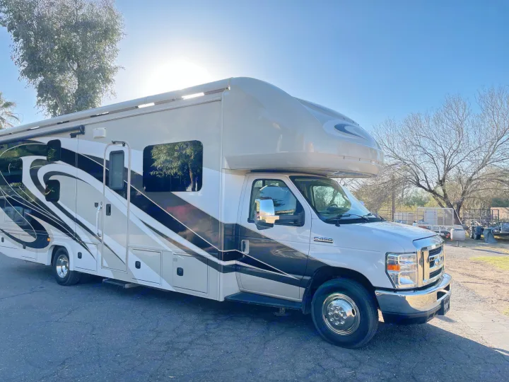 A large Class C RV rental, white with striking beige & black designs, parked on asphalt under a sunny sky.. Jamboree Jamboree Motorhome 2017