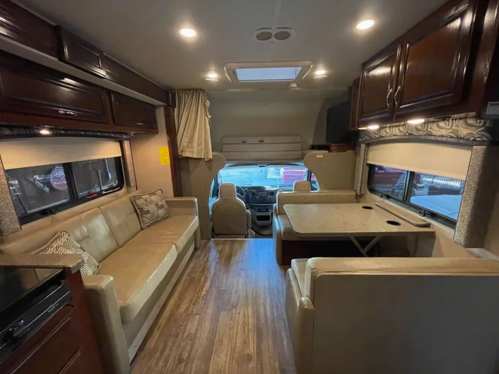 Inside a comfortable RV rental: living room couch, dining table, kitchen counter, and cockpit view.. Jamboree Jamboree Motorhome 2017