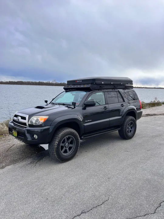 Black Toyota 4Runner with iKamper rooftop tent by the water, ready for your next rv rental overlanding adventure.. Toyota 4runner 2006