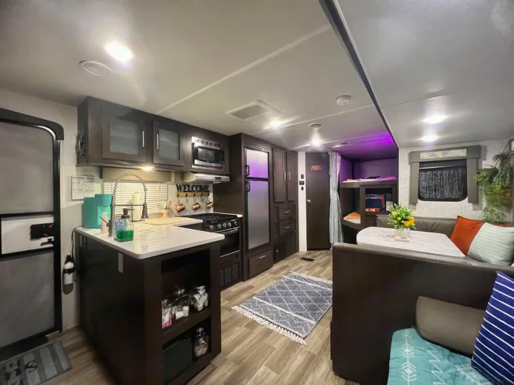 Inside a modern **rv rental**: full kitchen with island, dining area, and bunk beds. Bright & inviting.. Forest River Wildwood 2020