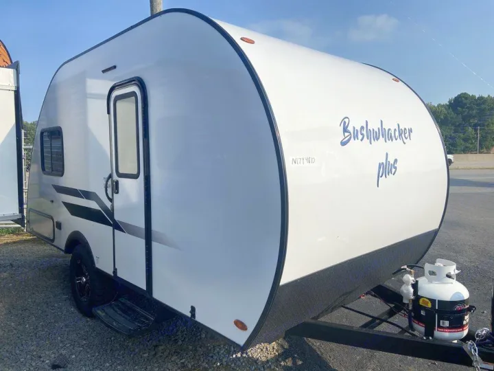 White Bushwhacker Plus travel trailer RV rental, featuring a rounded front and propane tanks, ready for adventures.. Braxton Creek Bushwhacker Plus 2021