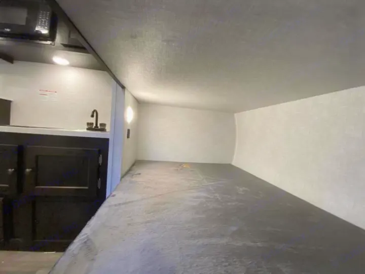 Inside this RV rental, a cozy low bunk bed dominates, with a compact counter, sink, and overhead microwave to the left.. Braxton Creek Bushwhacker Plus 2021