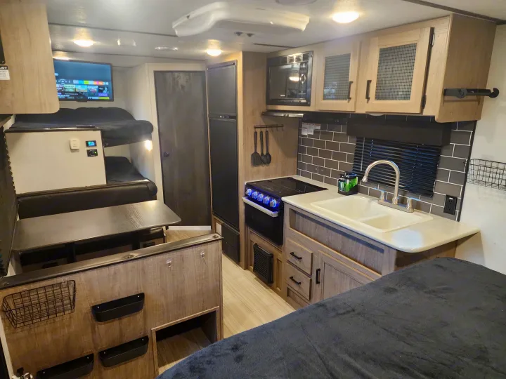 Modern RV rental interior featuring a kitchen, dinette, bunk beds, and main sleeping area. Ready for adventure!. Keystone RV Hideout 2022