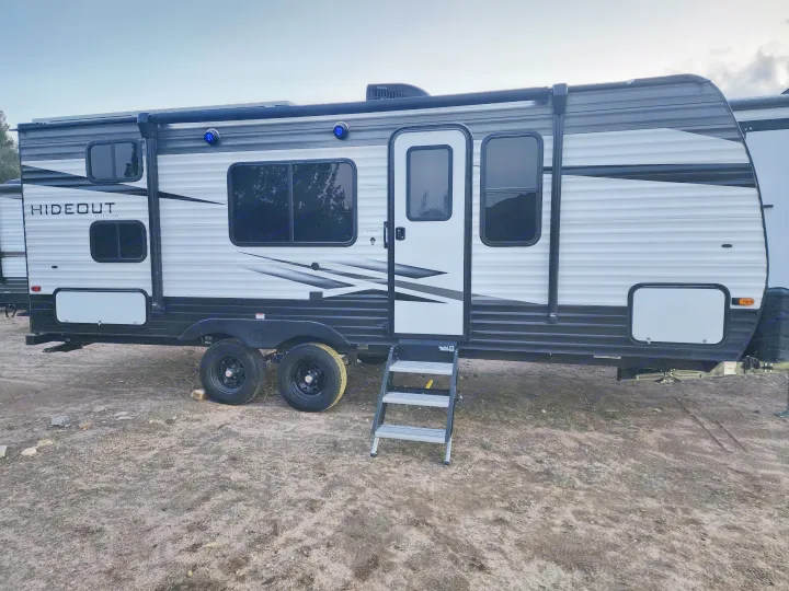 This white and black Hideout travel trailer, an RV rental with steps, is ready for your next outdoor adventure.. Keystone RV Hideout 2022