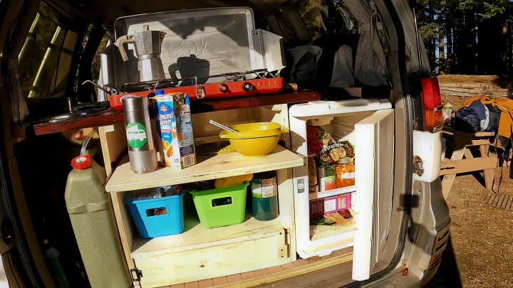 RV rental interior: organized camper kitchen with stove, open fridge, and water supply for adventurers.. nissan elgrand 1997