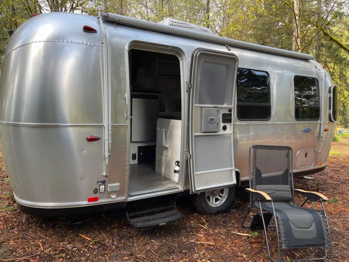 Explore nature with this Airstream travel trailer RV rental, parked outdoors with its door open, inviting adventure.. Airstream Sport 2019