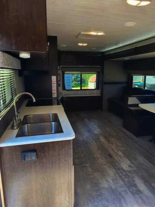 Modern RV rental interior showcasing a full kitchen with double sink, sofa, and dining booth.. Heartland RVs Pioneer 2020
