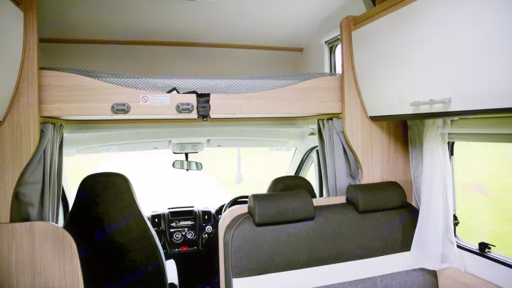 RV rental interior: Looking forward to the cab, featuring an overhead bunk, front seats, and storage. Ideal for travel.. Sunlight A72 2023
