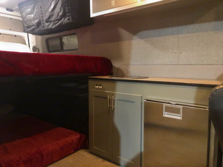 Inside an RV rental: features include bunk beds, a compact kitchenette with a fridge, and overhead storage.. Freightliner Sprinter 2012
