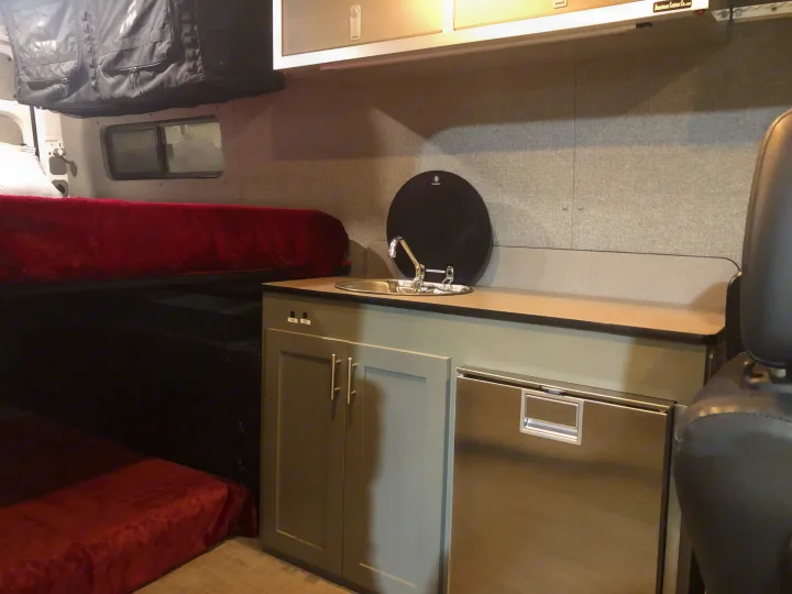 Experience comfort in this RV rental: compact kitchen with sink and fridge, plus a bed and overhead storage.. Freightliner Sprinter 2012