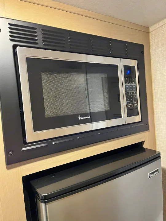 This RV rental kitchen features a built-in Magic Chef microwave above a compact Magic Chef refrigerator.. Forest River Geo Pro 19BH (bunk house) 2023