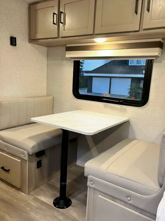 Modern RV rental dinette with light upholstered benches, a square table, and overhead cabinets, ideal for travelers.. Forest River Geo Pro 19BH (bunk house) 2023