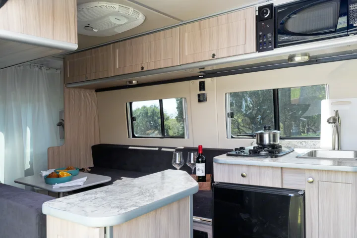 Inside this RV rental: A compact kitchen with stove, sink, and microwave, plus a dining area and comfortable seating.. Hymer Sunlight Van 1 2018
