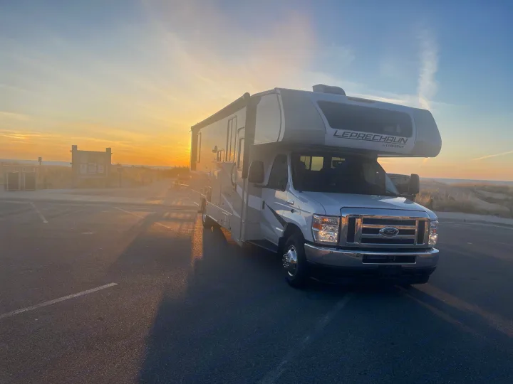 Golden hour glow on a parked Coachmen Leprechaun RV rental by the beach, ready for travel and coastal adventures.. Coachmen Leprechaun 2023