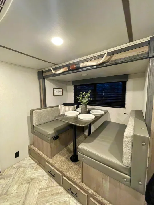 Modern RV rental interior with a cozy dinette, booth seating, and a table set for dining. Ideal for travel trailer adventures.. Keystone Springdale 2021