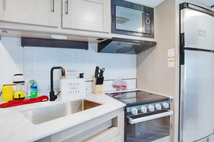 RV rental kitchen showcasing a clean sink, modern appliances (oven, microwave, fridge), and light wood cabinets.. Cruiser Rv Corp Shadow Cruiser 2021