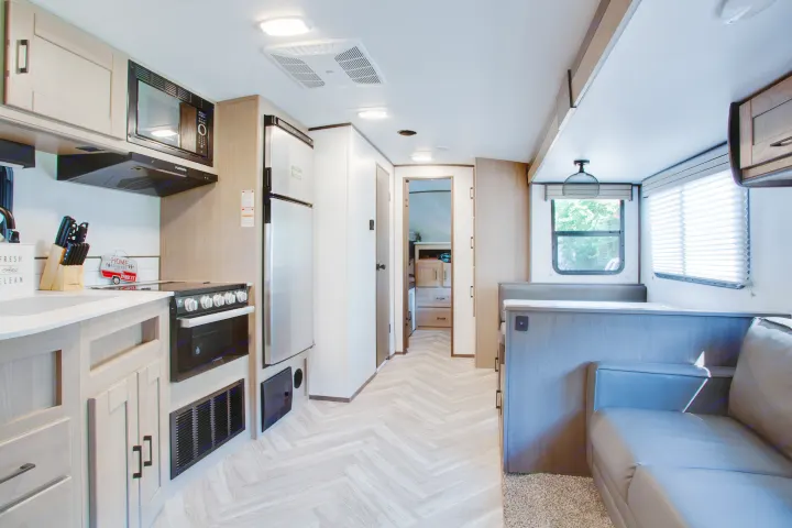 Bright RV rental interior: modern kitchen, dining booth, comfy living space, and hallway view.. Cruiser Rv Corp Shadow Cruiser 2021