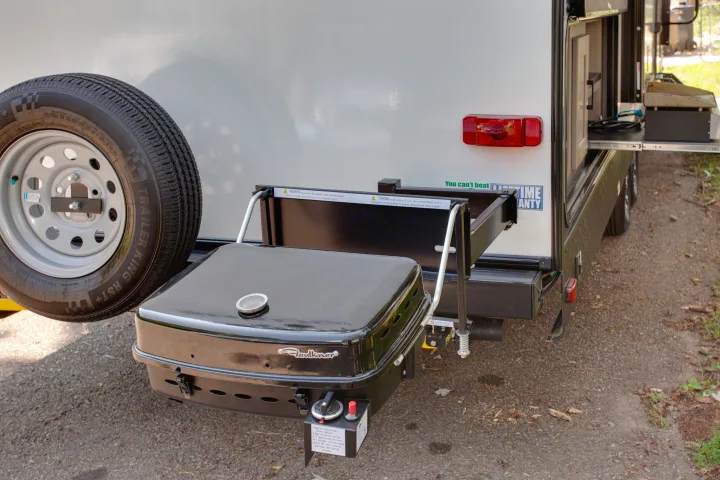 Rear of an RV rental with an outdoor kitchen featuring a mounted grill and spare tire, ready for outdoor cooking.. Cruiser Rv Corp Shadow Cruiser 2021