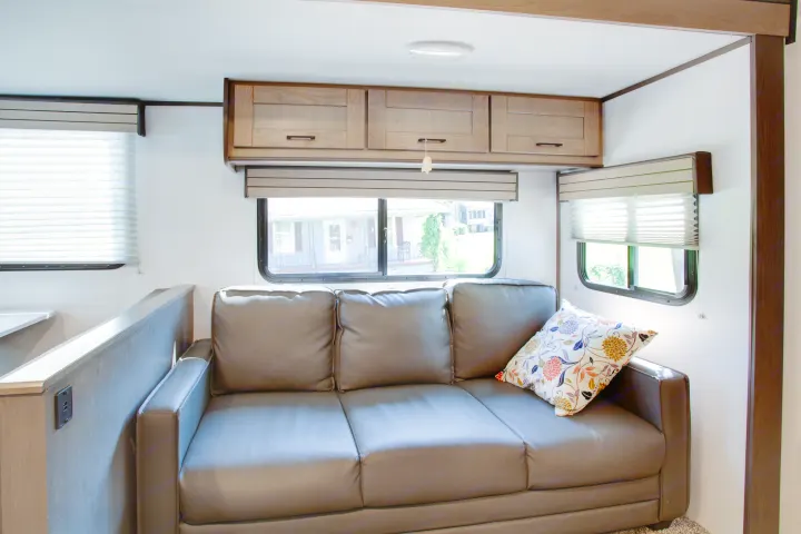 Spacious RV rental living area with a comfy sofa, wood cabinets, and large windows offering exterior views.. Cruiser Rv Corp Shadow Cruiser 2021