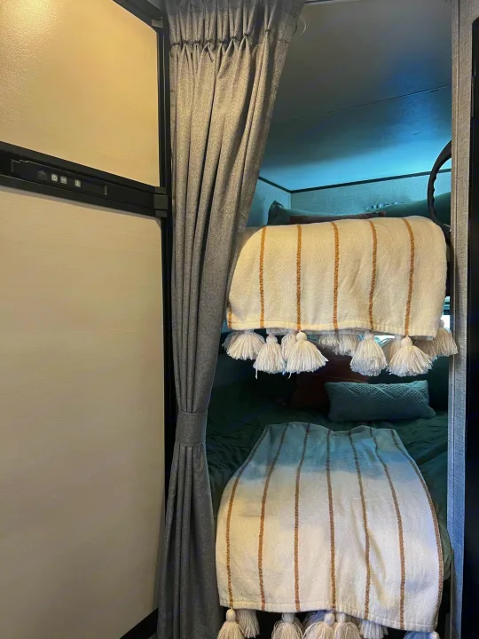 RV rental interior shows cozy bunk beds with throws and a refrigerator, offering comfortable camper living.. Jayco Featherlight SLX8 2022