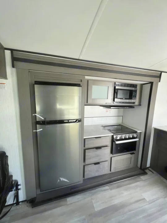 RV rental kitchen featuring a modern stainless steel refrigerator, microwave, stove/oven, and storage for comfortable travels.. Cruiser Rv Corp MPG 2700TH 2022