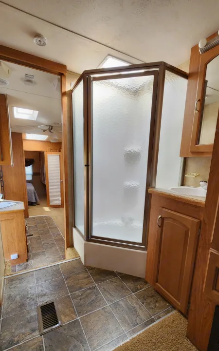 RV rental interior: A bright bathroom with a spacious shower, sink, and tiled floor, adjacent to the bedroom. Clean and modern.. Forest River Wildcat 2008